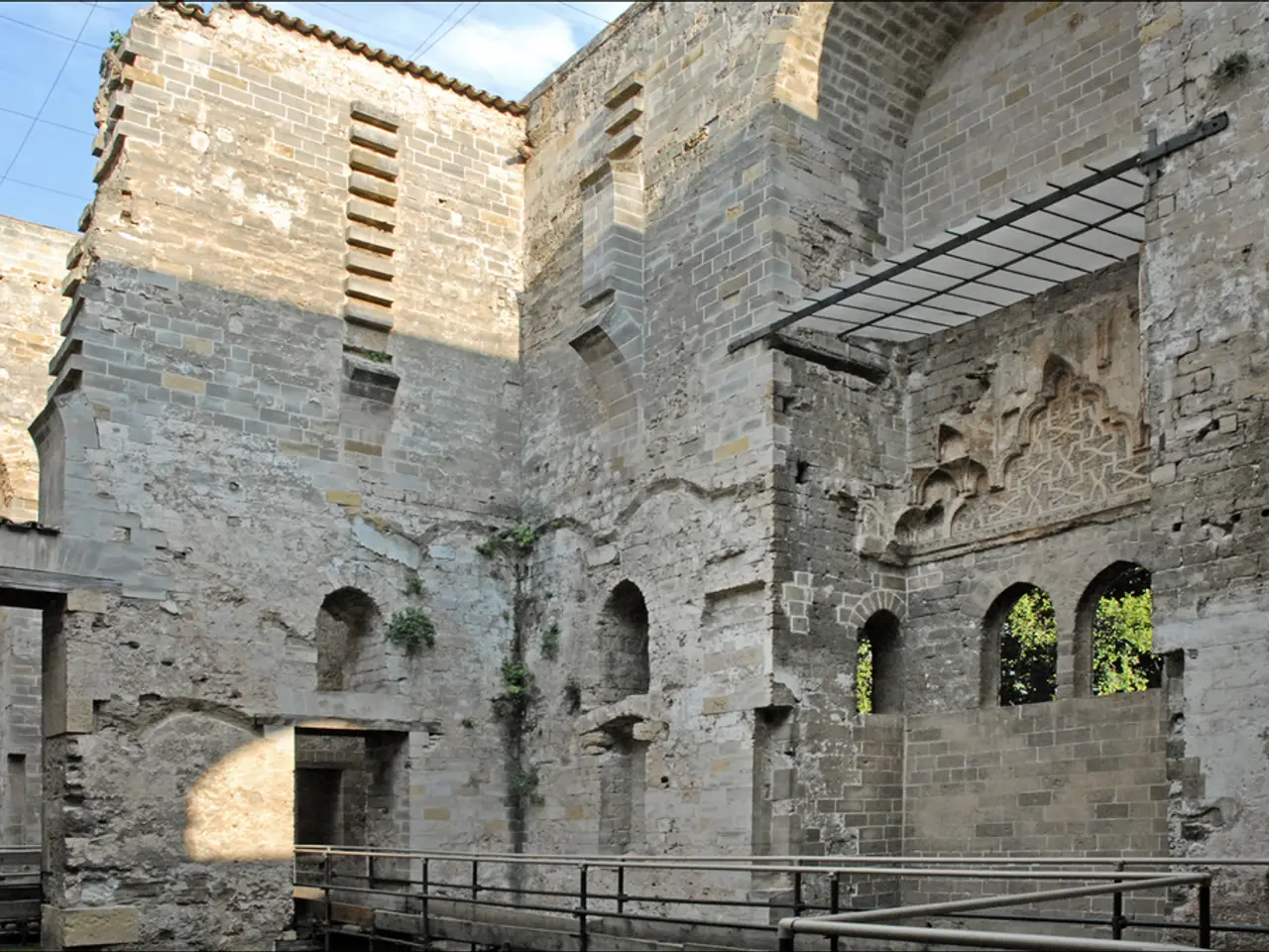 In this picture there is a old granite fort with arch design windows. In the front there is a pipe...