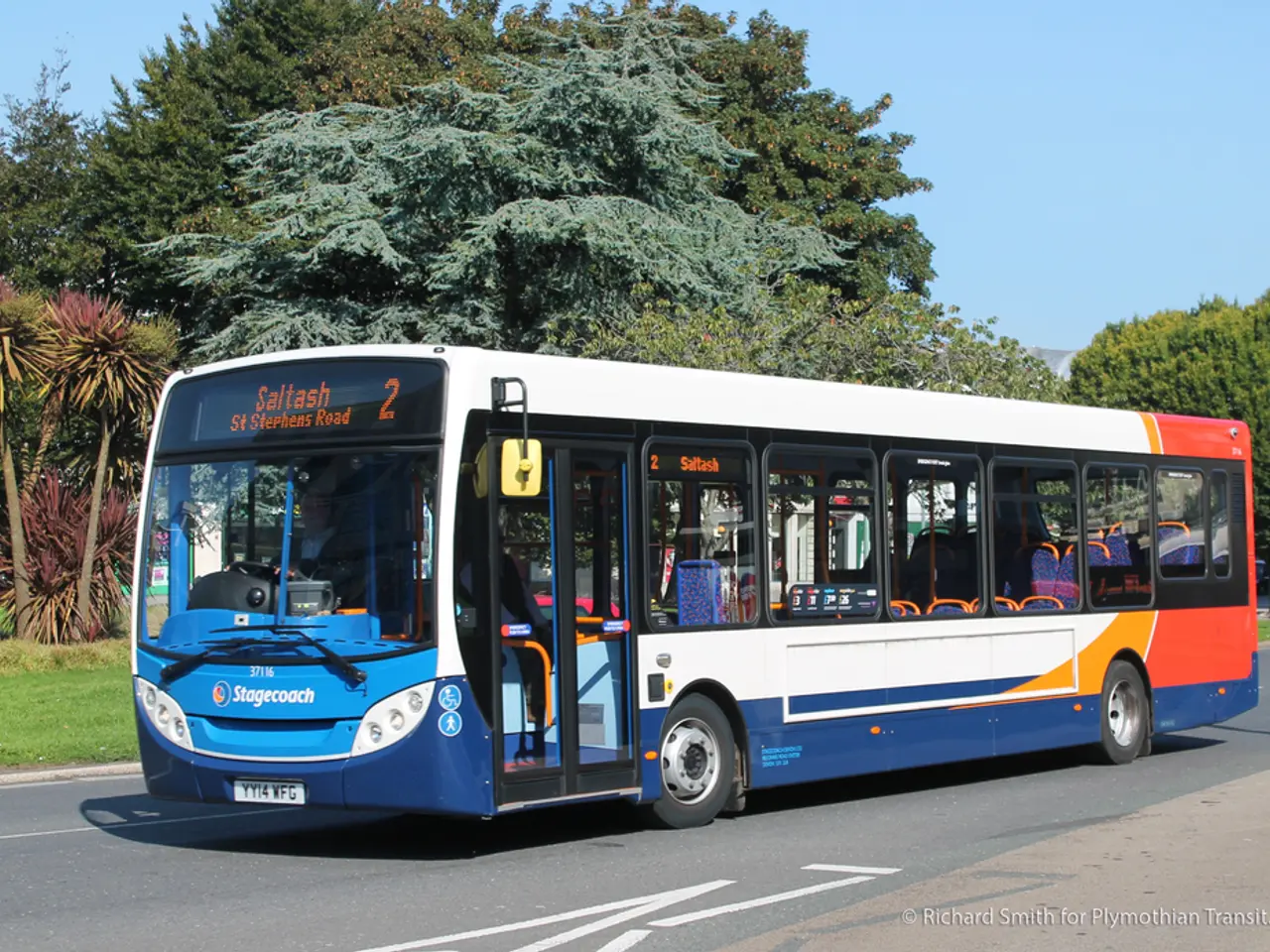 In this image in the center there is a bus which is moving on the road. In the background there are...