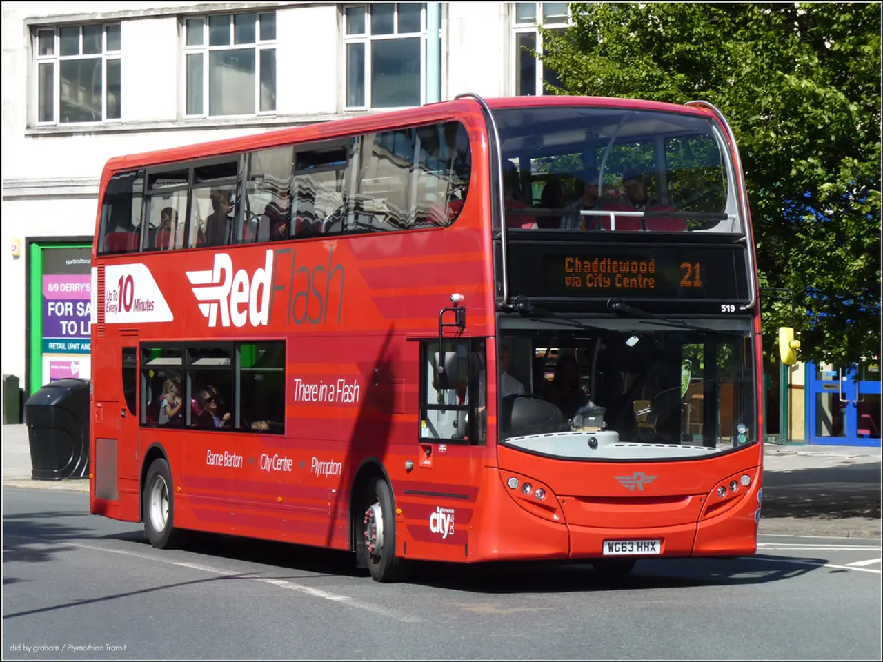 In this image in the center there is a bus which is red in colour with some text written on it and...