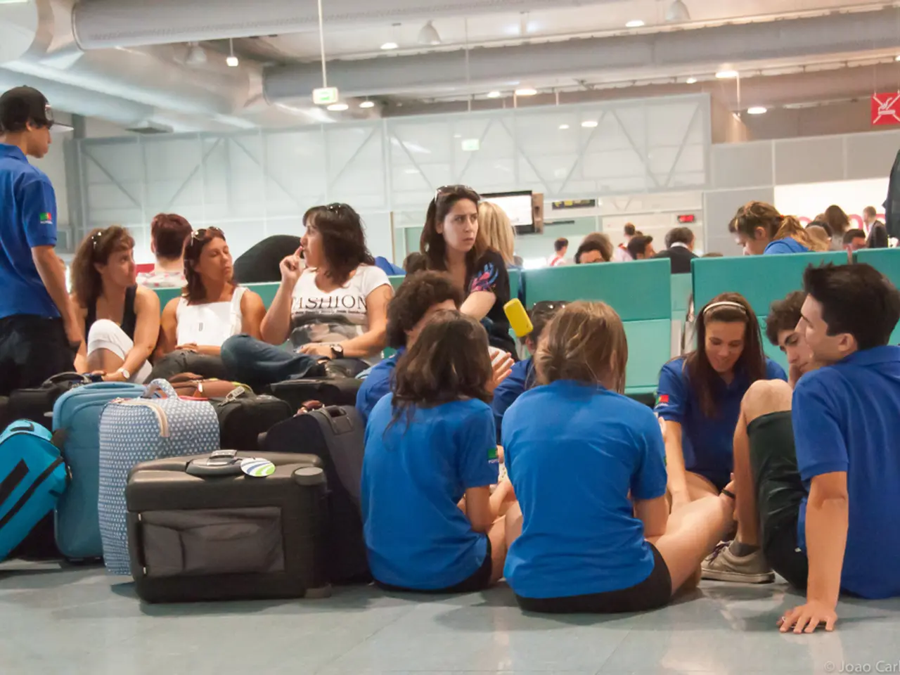 It is an airport, the picture is inside an airport, there are many people waiting for the flights,...