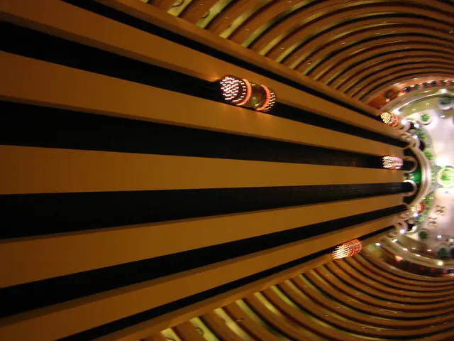 In the image there is a building with elevators going up and down and above there are lights.