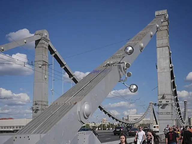 In the image there are some poles and other equipment, around them there are vehicles on the road...