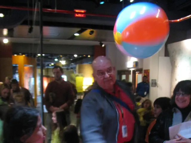 In this image we can see people standing on the floor, electric lights and decors.