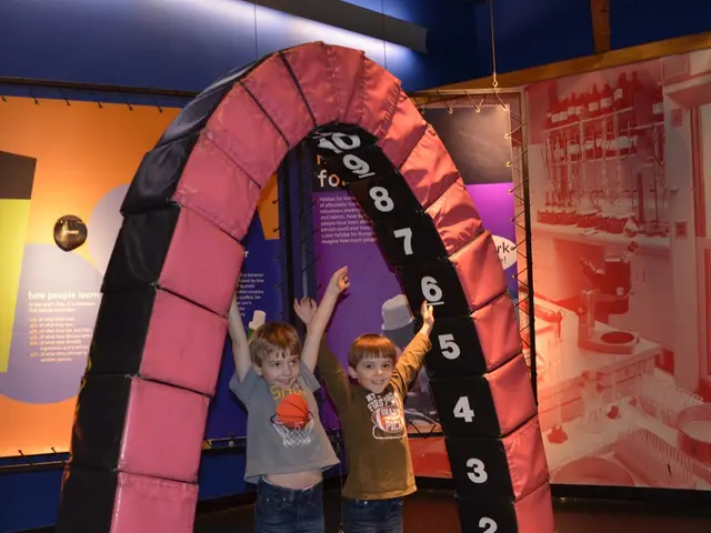 In this image, there are kids and we can see an archetype fun ride and there are boards. At the...