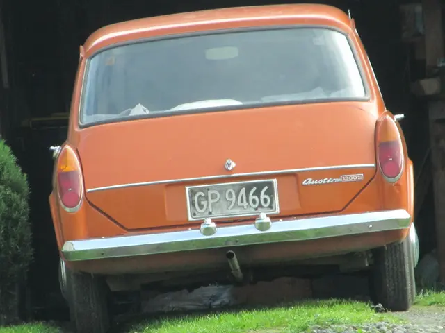 In the center of the image we can see a car. At the bottom there is grass. On the left there is a...