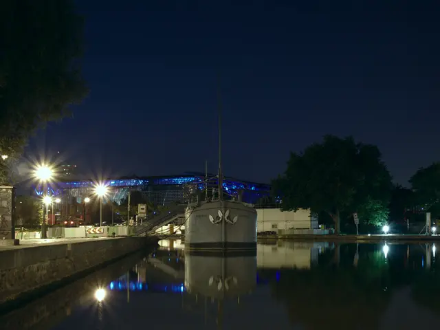 In this image there are few buildings, a tank and some reflections in the water, stairs, street...