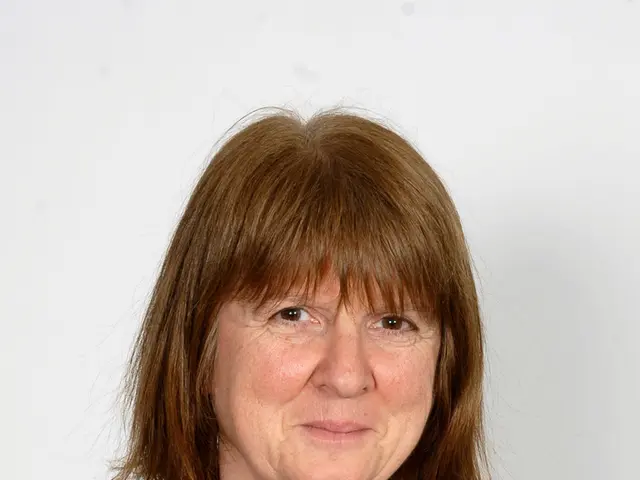 In this image we can see a women with brown hair wearing black coat and white t shirt.