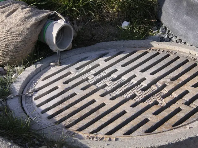 The picture consists of a pothole. On the left there are grass, stones, bag and pipe. At the top...