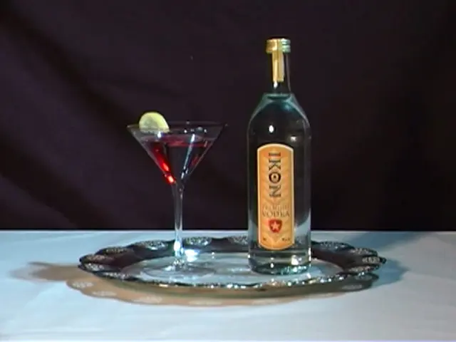 A wine glass and vodka bottle are placed on a table.