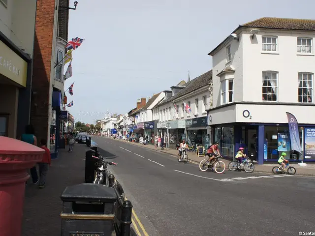 In this image there is a road in the middle. There are buildings on either side of the road. On the...
